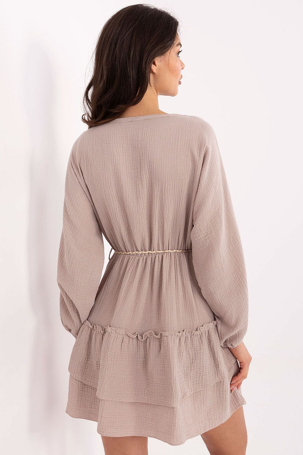 Woman wearing a light yellow dress with long sleeves on a white background