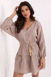 Woman wearing a light yellow dress with long sleeves on a white background