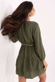 Woman wearing a light yellow dress with long sleeves on a white background