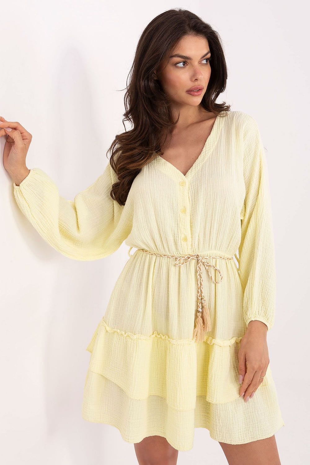 Woman wearing a light yellow dress with long sleeves on a white background