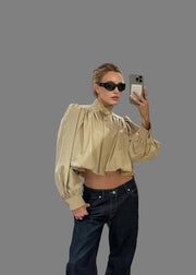 Person taking a mirror selfie in a clothing store with a dog on a chair.