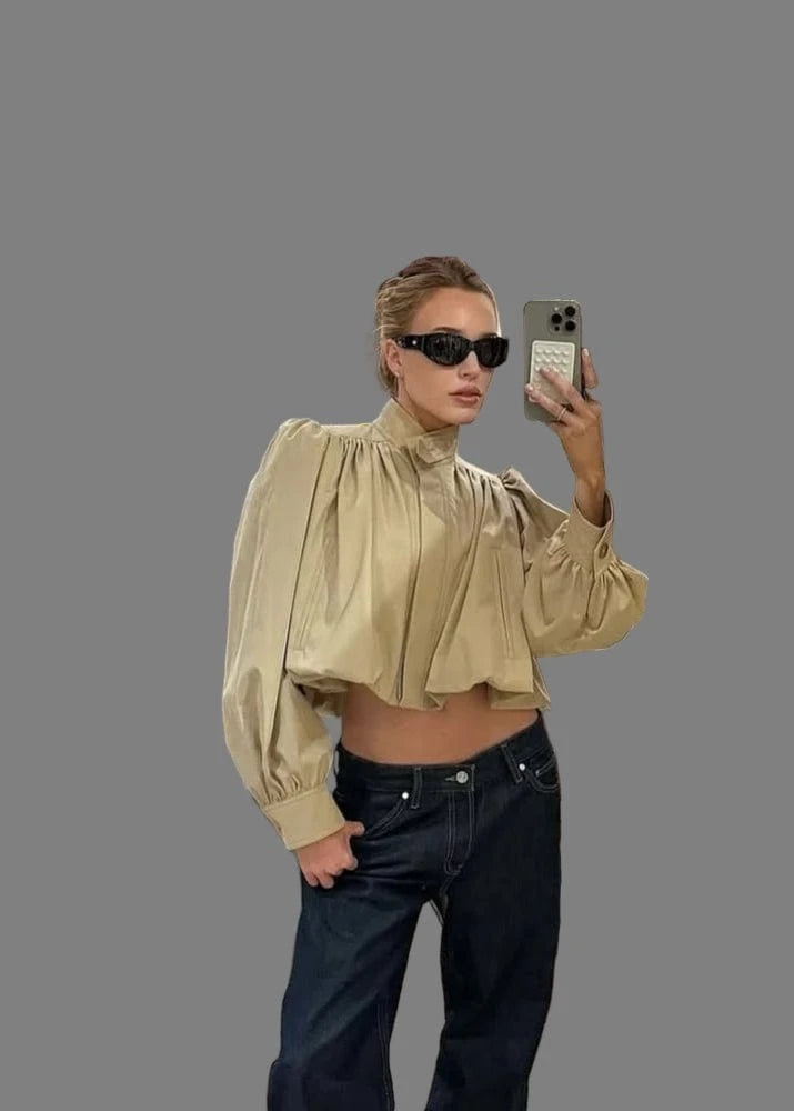 Person taking a mirror selfie in a clothing store with a dog on a chair.