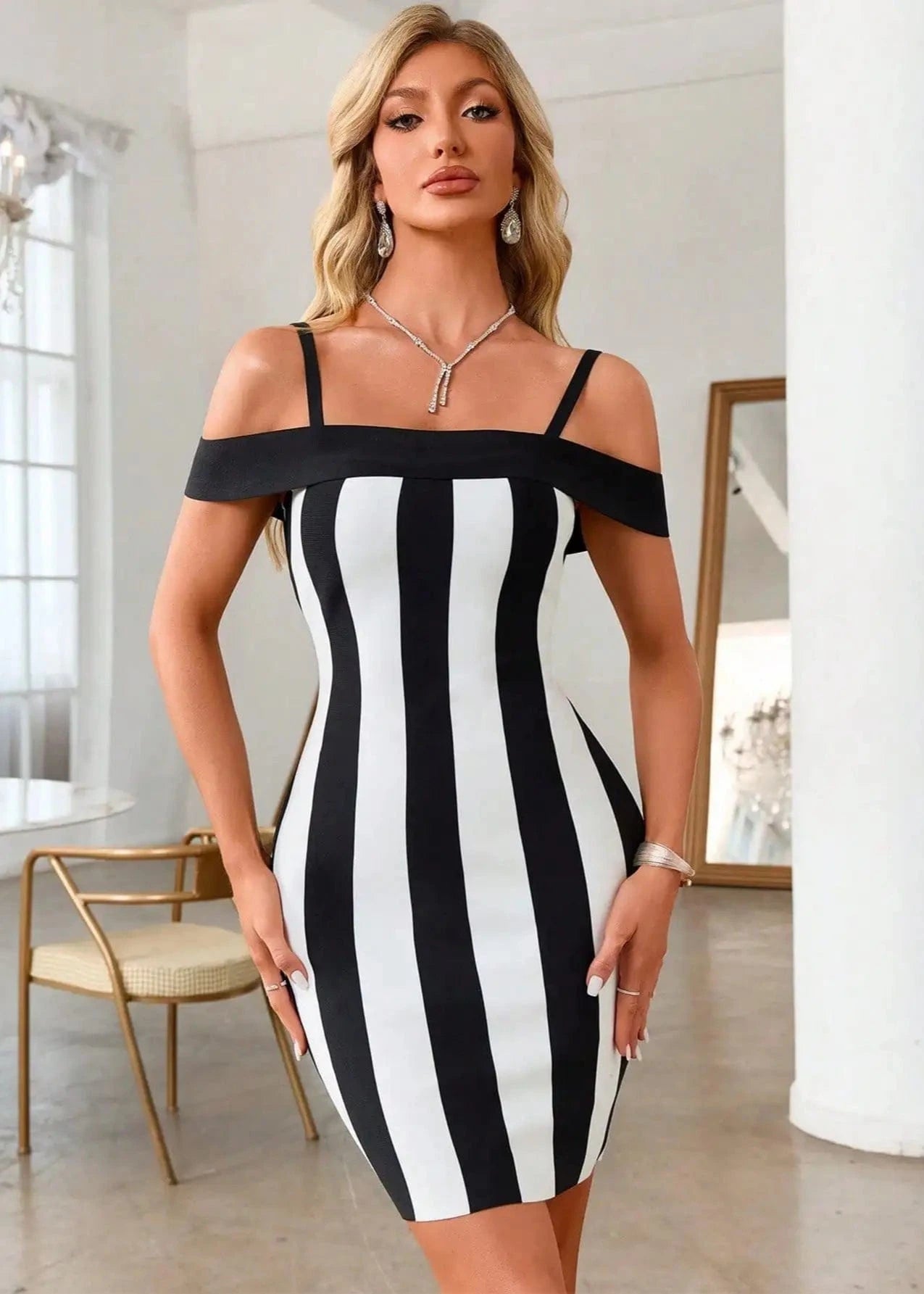 Woman wearing a black and white striped dress in a bright room.