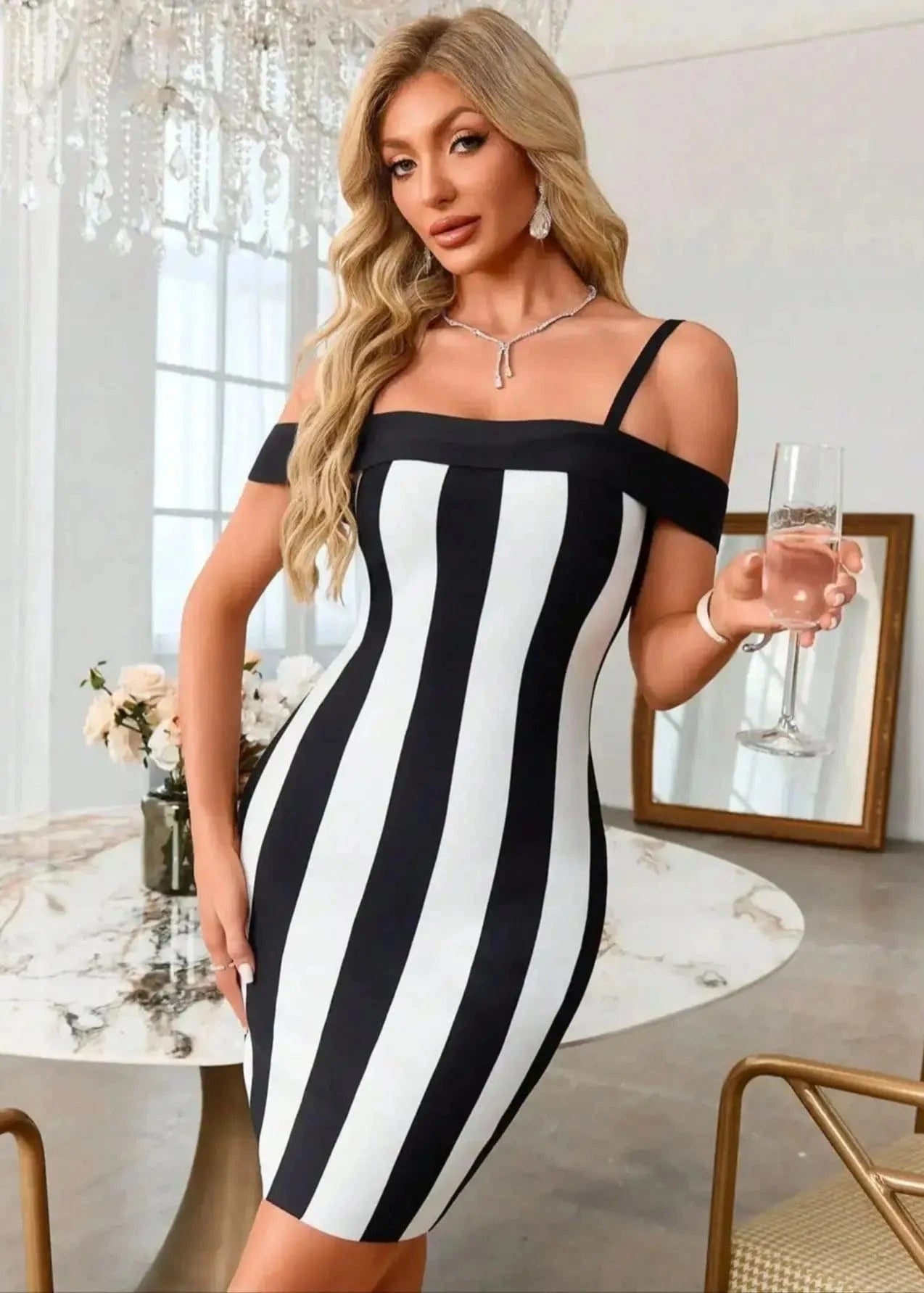 Woman in a black and white striped dress holding a glass in an elegant room.
