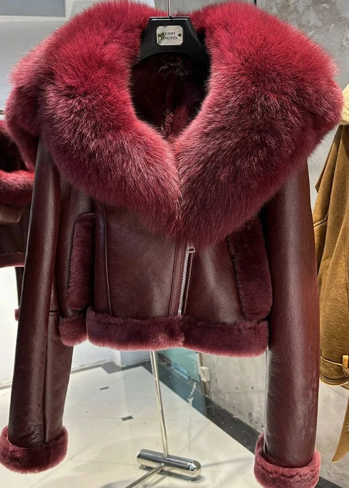Brown leather jacket with a large fur collar on a rack.