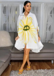 Woman wearing a white dress with a large yellow flower design in a living room.