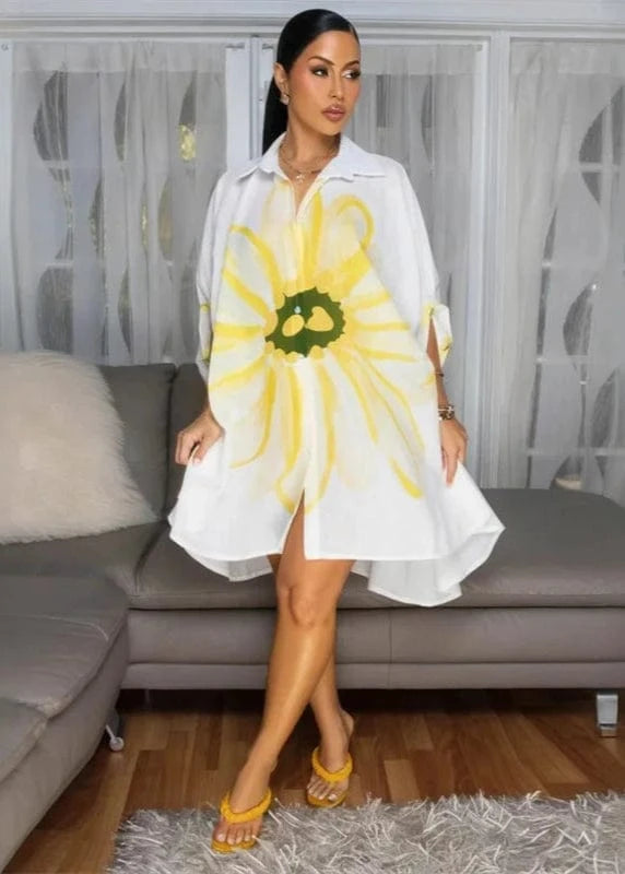 Woman wearing a white dress with a large yellow flower design in a living room.