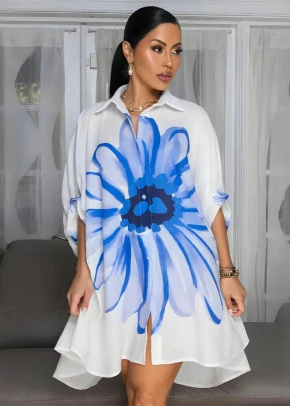Woman wearing a white dress with a large blue flower design in a room.