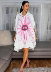 Woman wearing a white dress with a pink floral design in a living room.