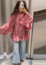 Person wearing a pink ruffled shirt and light blue jeans taking a mirror selfie.