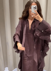 Person wearing a long, dark purple garment in a neutral setting