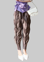 Person wearing brown textured pants and a purple top, standing on a wooden floor.