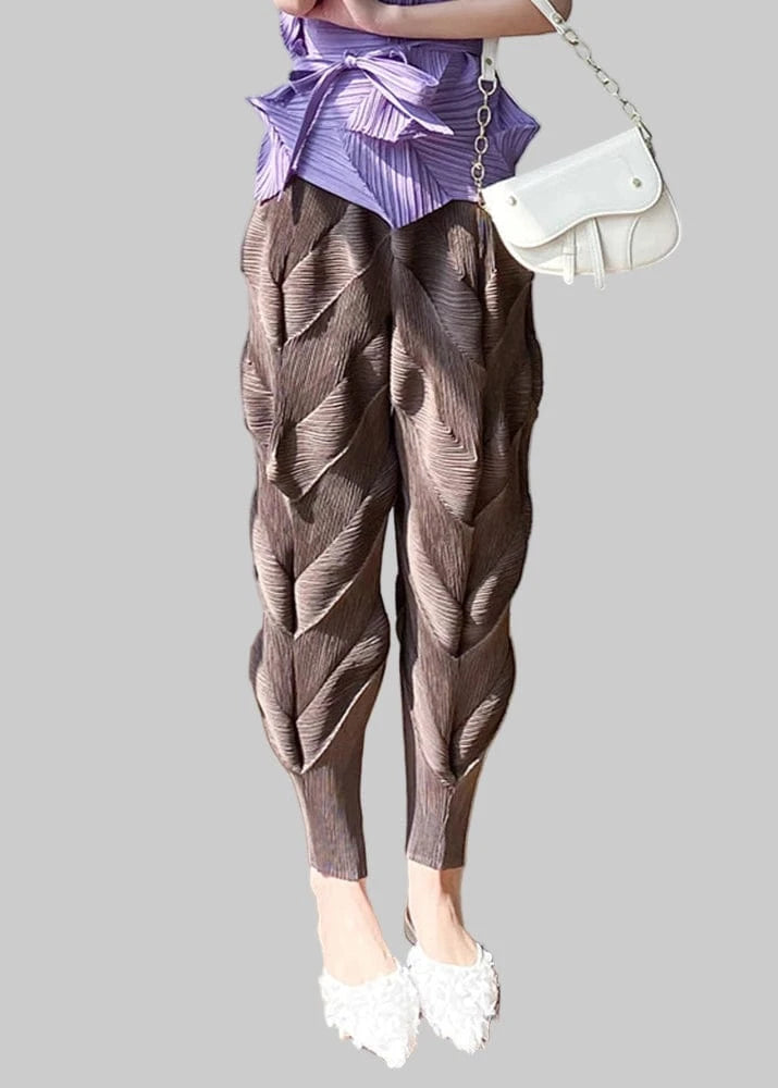 Person wearing brown textured pants and a purple top, standing on a wooden floor.