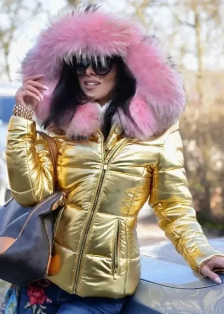 Person wearing a gold puffer jacket with a large pink fur hood in an outdoor setting.
