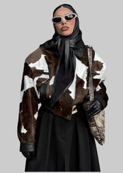 Person wearing a cow print coat with a black outfit and sunglasses in an urban setting