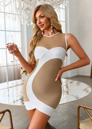 Woman in a beige and white dress holding a glass in an elegant room.