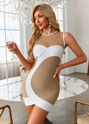 Woman in a beige and white dress holding a glass in an elegant room.