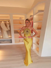 Woman in a yellow evening gown standing in a well-lit closet.