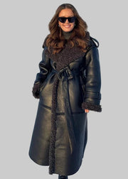 Woman wearing a black leather coat with fur trim in a snowy landscape