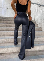 Person wearing black leather pants and a black coat on concrete steps.