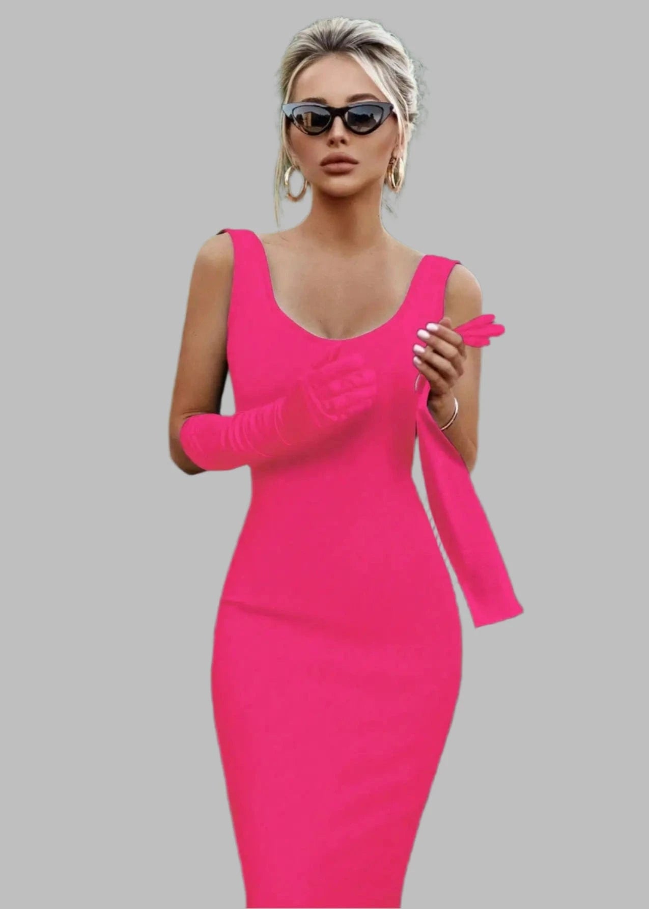 Woman in a bright pink dress and gloves standing next to a black car with greenery in the background