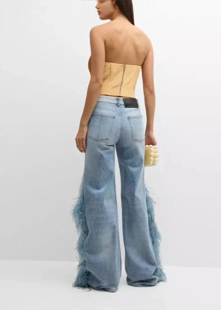 Woman wearing a strapless top and light blue flared jeans on a white background