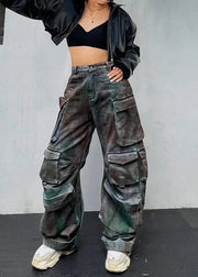 Person wearing camouflage cargo pants and a black jacket against a gray wall.