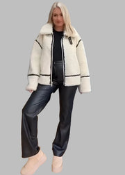 Woman wearing a white coat with black accents in a room, with close-up images of the coat on the right.