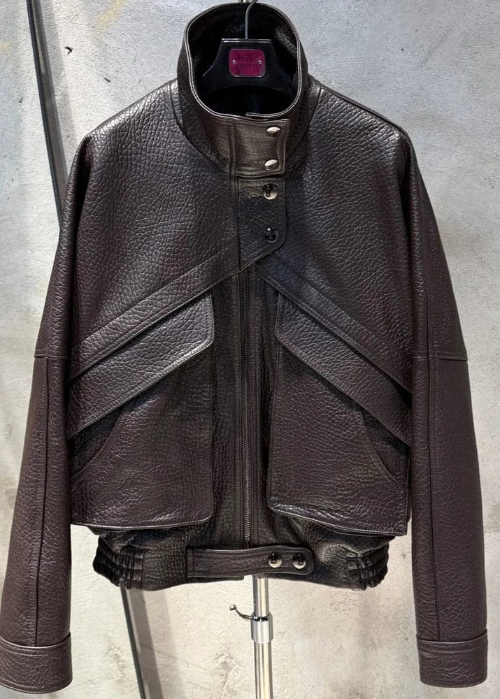 Brown leather jacket on a mannequin against a concrete wall.