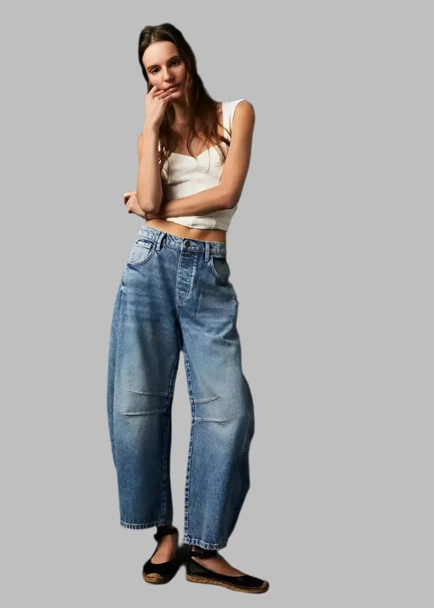 Woman wearing blue jeans and a white top against a dark background