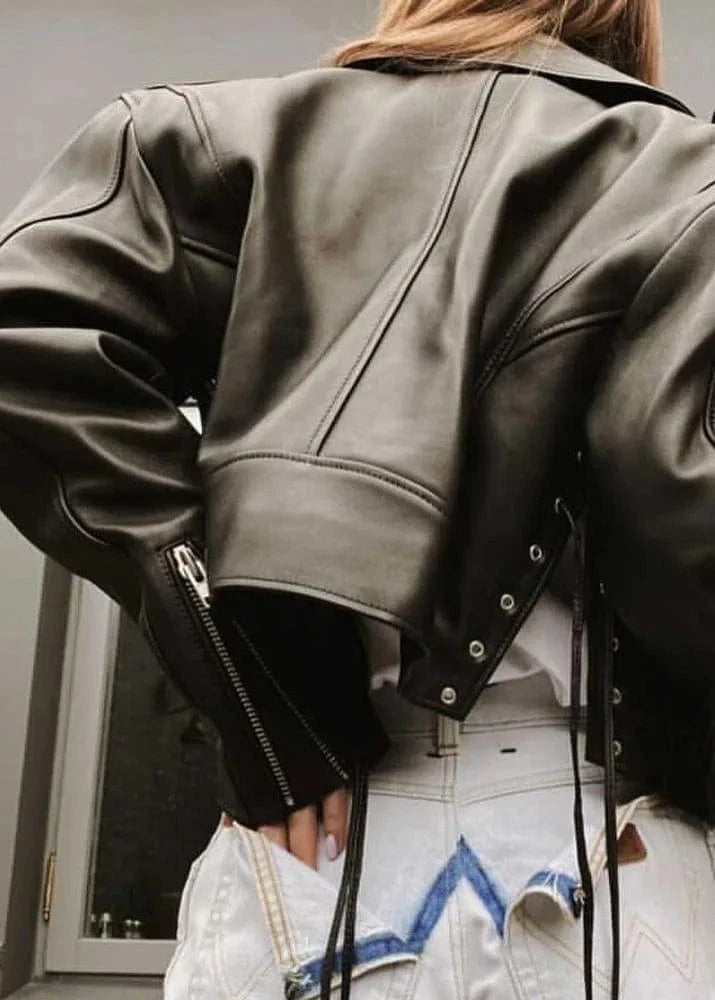 Person wearing a black leather jacket with a neutral background