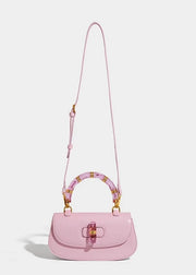 Pink handbag with a decorative handle on a light gray background