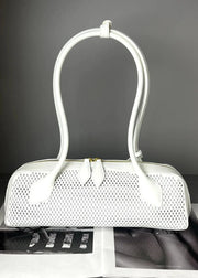 White handbag with perforated design on a gray background