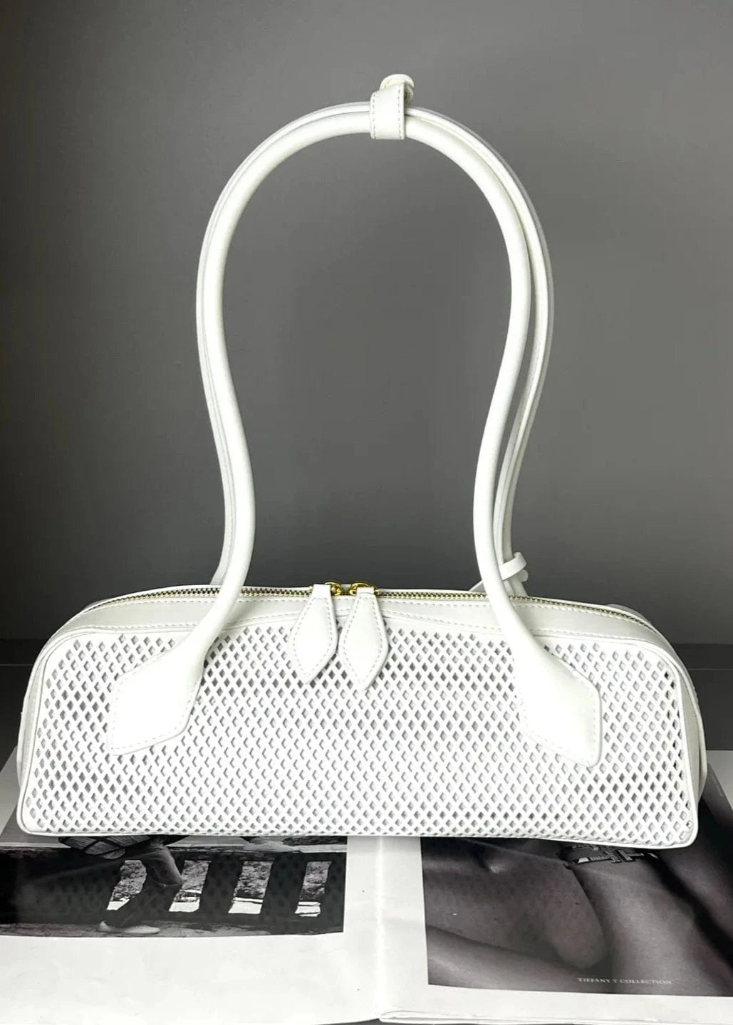 White handbag with perforated design on a gray background