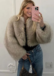Woman taking a mirror selfie wearing a fur coat and jeans.