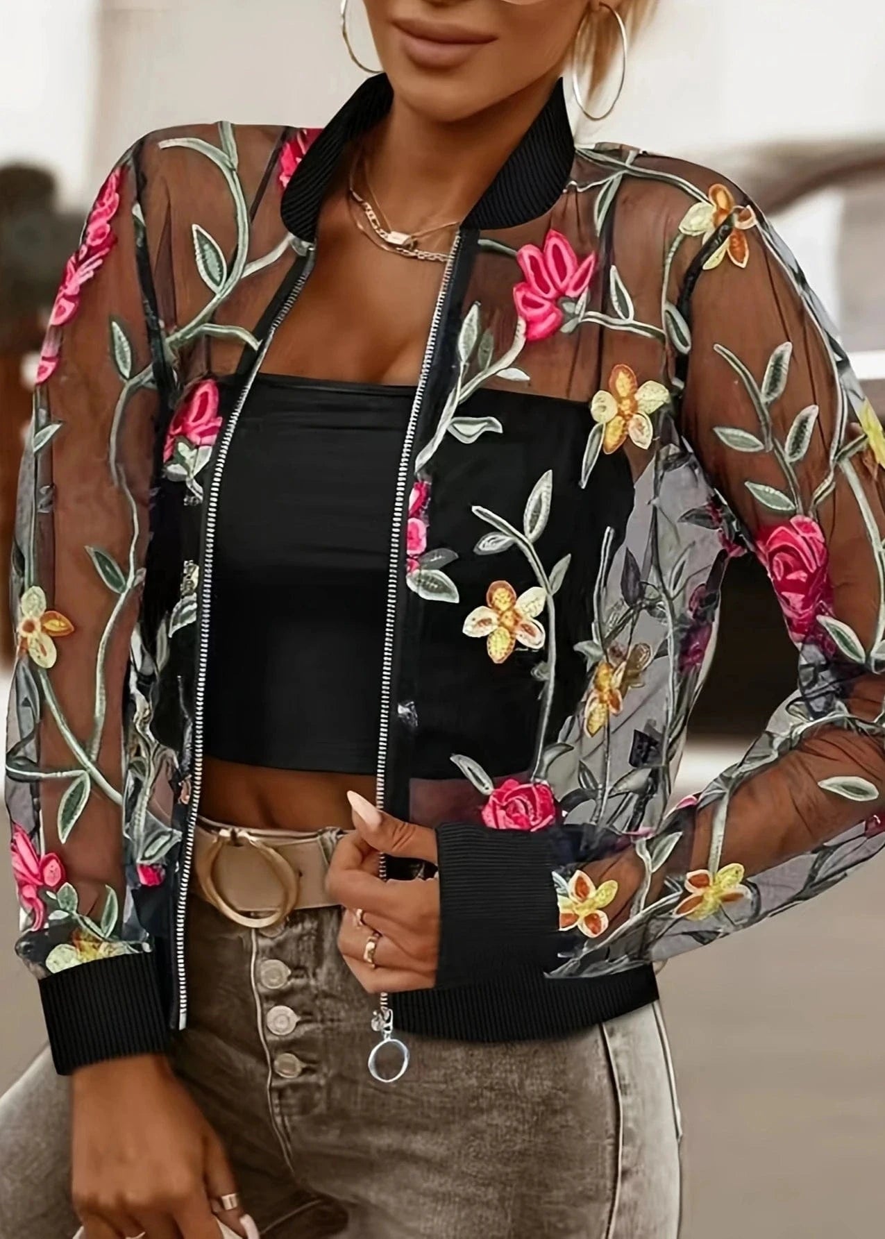 Woman wearing a floral embroidered bomber jacket with a blurred background