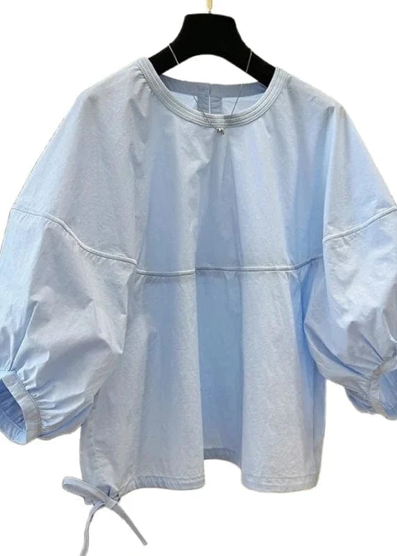 Light blue blouse with balloon sleeves on a hanger against a white background