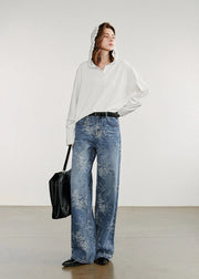 Woman wearing a white blouse and blue jeans with a black bag on a plain background