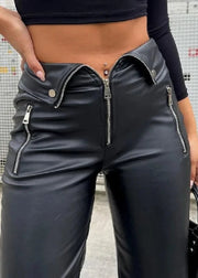 Person wearing black leather pants with zippers in an urban setting