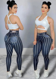 Woman wearing a white sports bra and blue striped leggings posing against a gray background.
