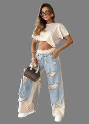 Woman in stylish outfit with ripped jeans and beige top in a modern living room.