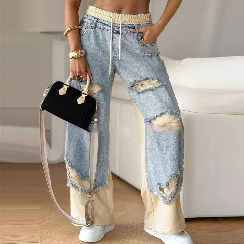 Person wearing ripped jeans with a black handbag indoors