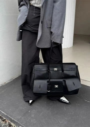Person holding a black leather bag against a neutral background