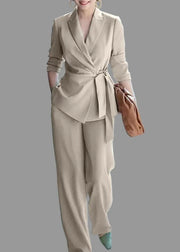 Woman wearing a beige suit with a brown handbag in an indoor setting