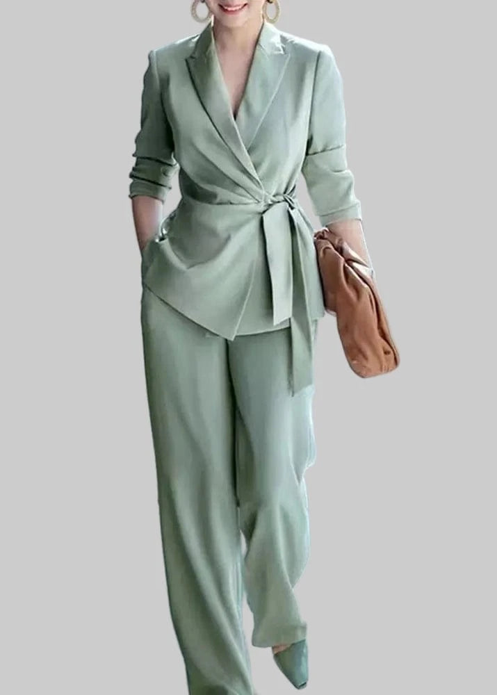 Woman in a light green suit holding a brown bag in an urban setting