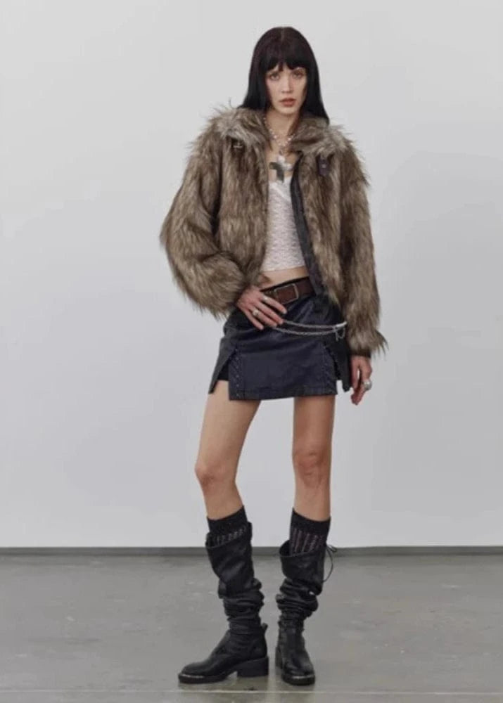 Person wearing a fur coat, white top, black skirt, and black knee-high boots on a plain background