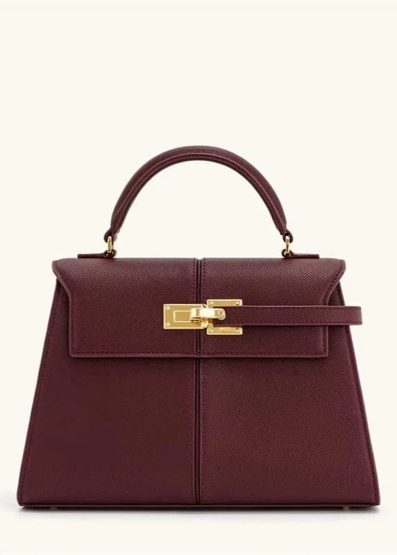 Maroon handbag with gold hardware on a white background