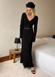 Woman wearing a black dress and hat in a bedroom setting