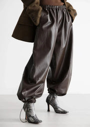 Brown leather pants worn with a brown coat on a white background
