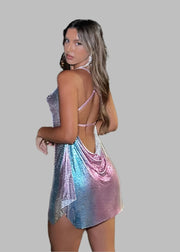 Woman in a colorful dress standing on a dock with city lights in the background